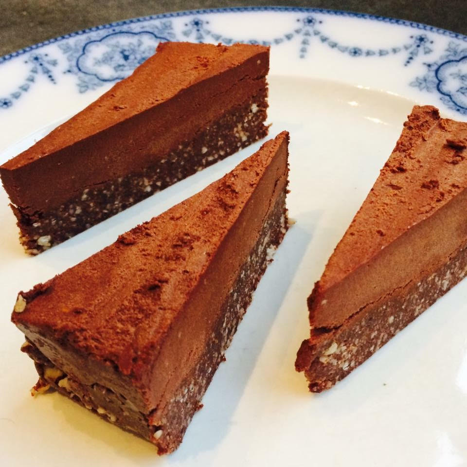 Rå lagkage med mandelbund og chokoladetopping skåret i stykker