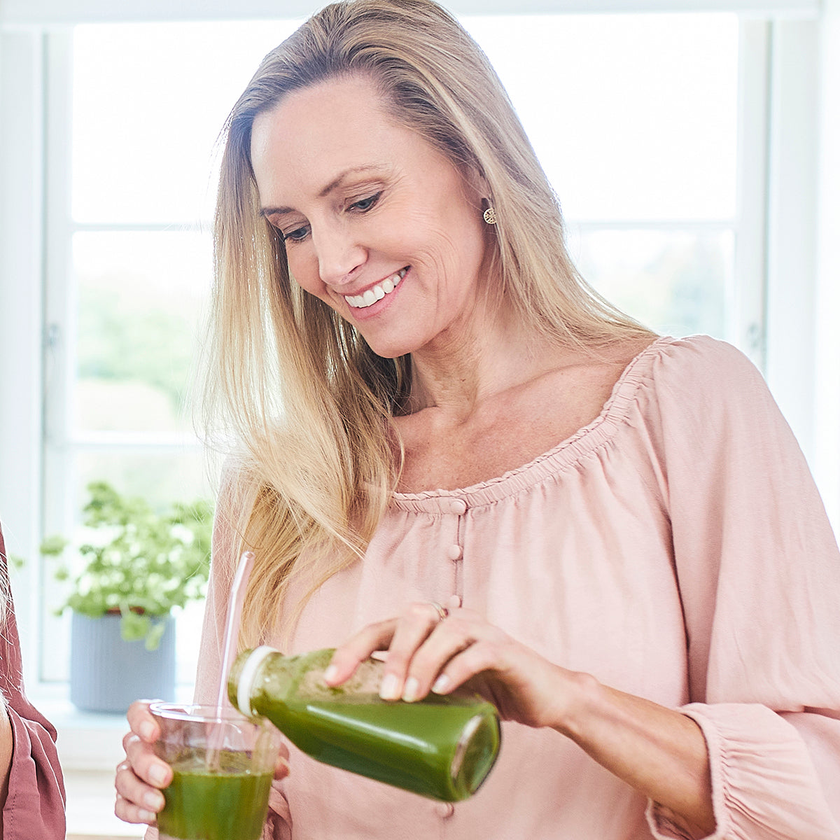 Carolina Cia Bruun i køkkenet med en grøn smoothie